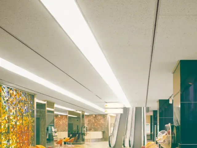 Daiken Ceiling Board terpasang di lobi gedung dengan lampu memanjang dan eskalator